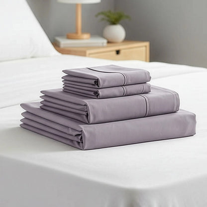 Stacked grey queen sheets with deep pockets, neatly folded on a bed