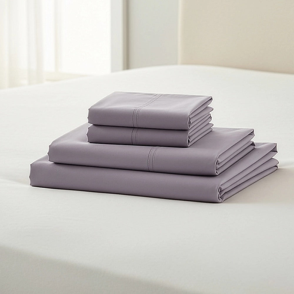 Grey king bed sheet set with folded stacks on a bed surface