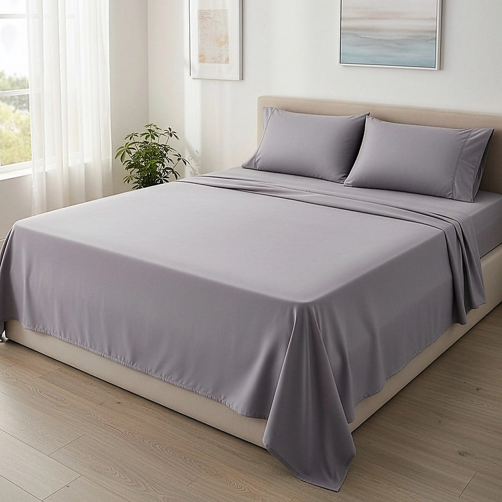 Grey king sheet set on a bed with two pillowcases and draped flat sheet