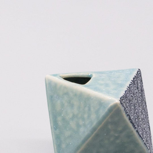 Turquoise triangular ceramic vase with open top and blue wave border.