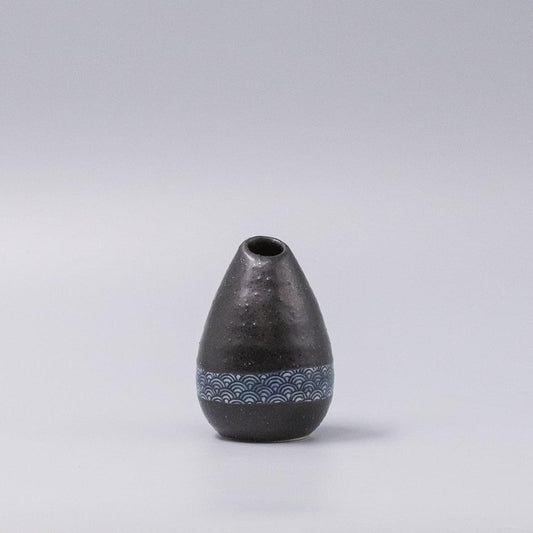 Black ceramic bud vase with textured surface and blue wave band near base
