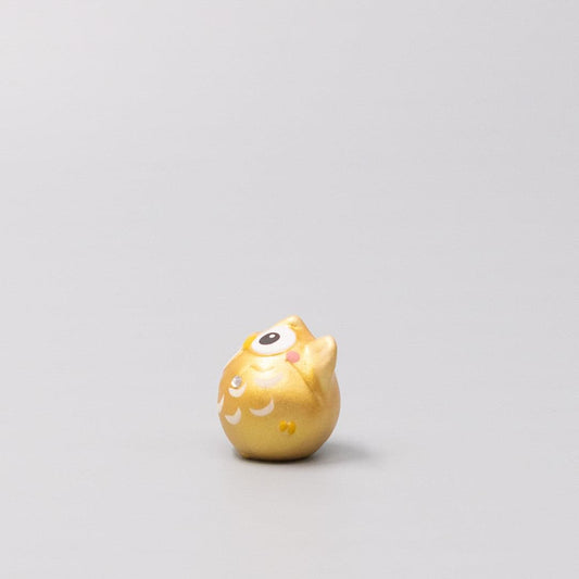 Gold owl figurine, side profile with painted face and curved wing pattern