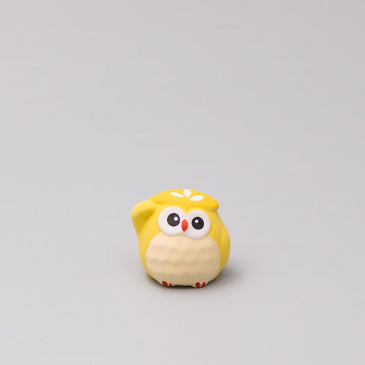Yellow plush owl figurine with white belly, red accents, and large cartoon eyes