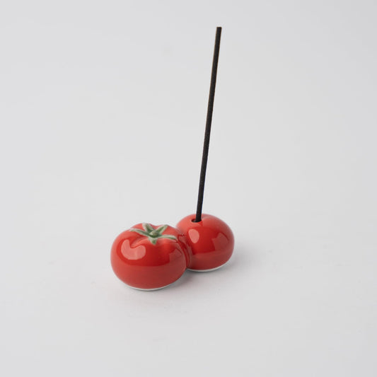 Red tomato incense holder with inserted incense stick