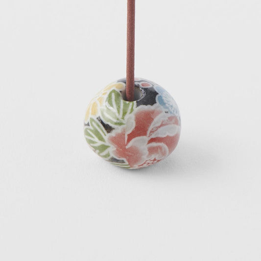 Round incense stand with floral bead design, incense stick inserted