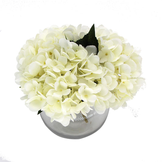 Artificial white hydrangea blooms in gray glass vase with dark leaves