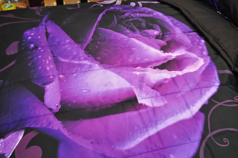 Purple rose comforter detail on black fabric with swirling vine accents