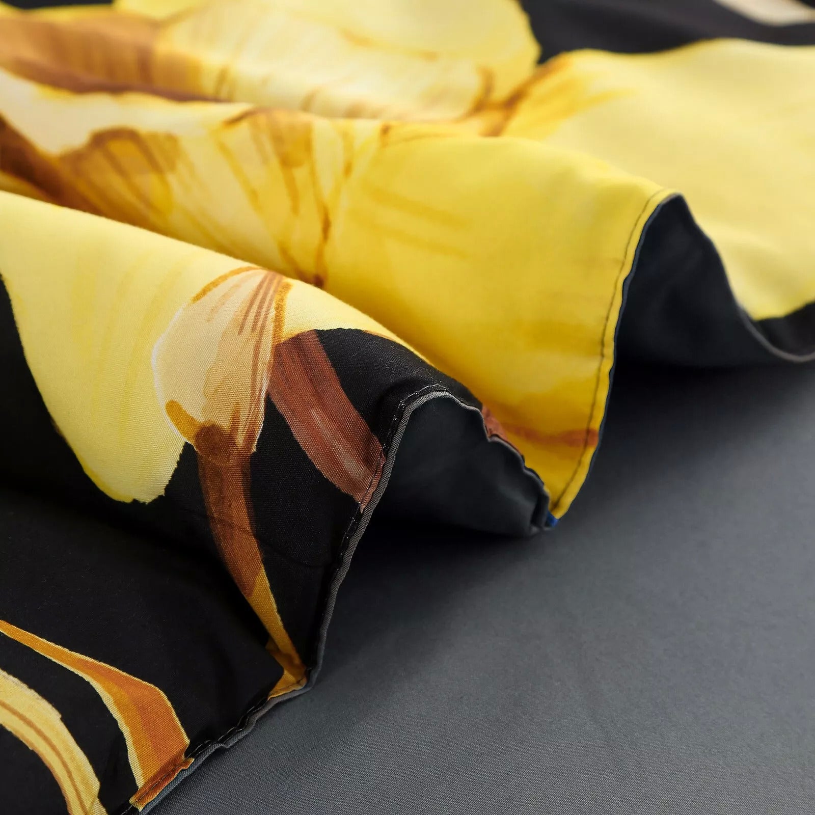 Comforter fabric close-up with black floral print and yellow petal accents