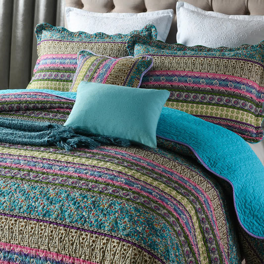 Teal and multicolor striped quilt top with matching pillowcases on a bed