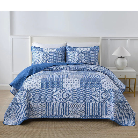 Blue-and-white quilted bedspread with two patterned pillow covers on a queen bed