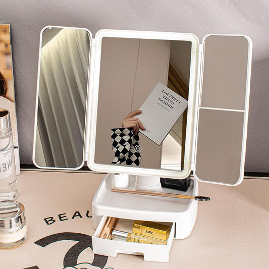 Tri-fold LED vanity mirror with illuminated frame and open storage drawer, white shell