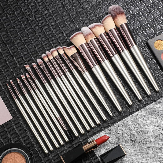 Makeup brushes with silver handles and beige bristles on textured black mat