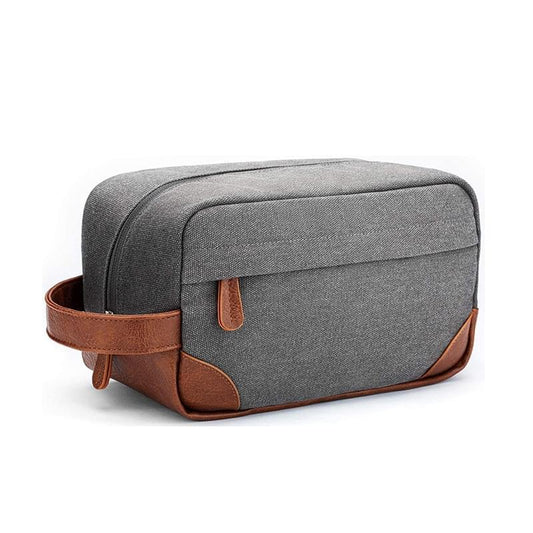 Grey canvas toiletry bag with brown leather trim, front strap, and top handle.