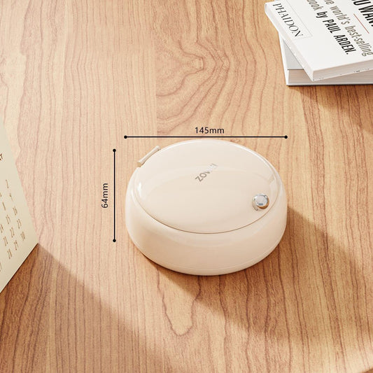 Beige round sewing kit organizer with closed lid on a wooden surface