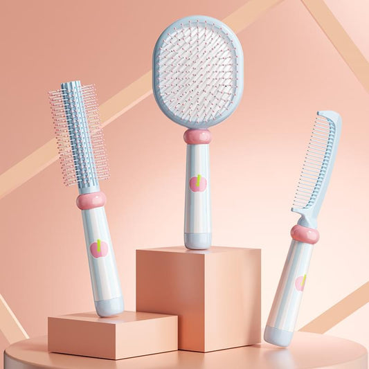 Three-piece hair brush set with round air-cushion brush and two comb brushes, blue bristles and pink grips.
