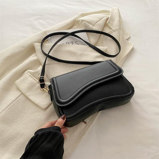 Black minimalist crossbody bag with top flap and adjustable shoulder strap
