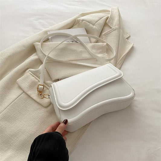 White minimalist crossbody bag with front flap, gold clasp, and shoulder strap