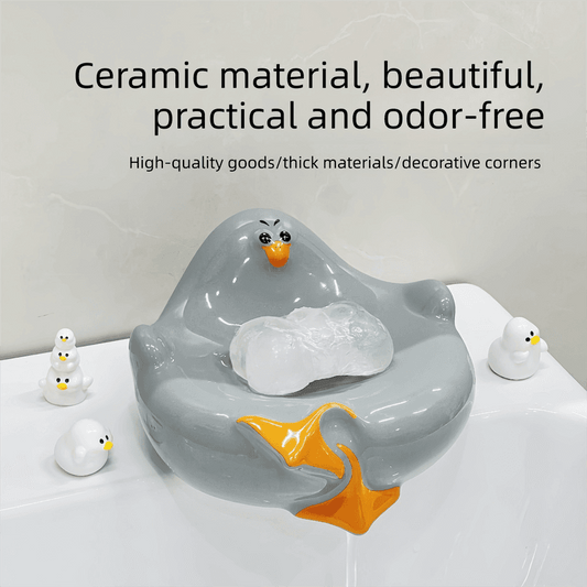 Grey ceramic seagull soap dish holding a white bar of soap, drainage on top, orange beak