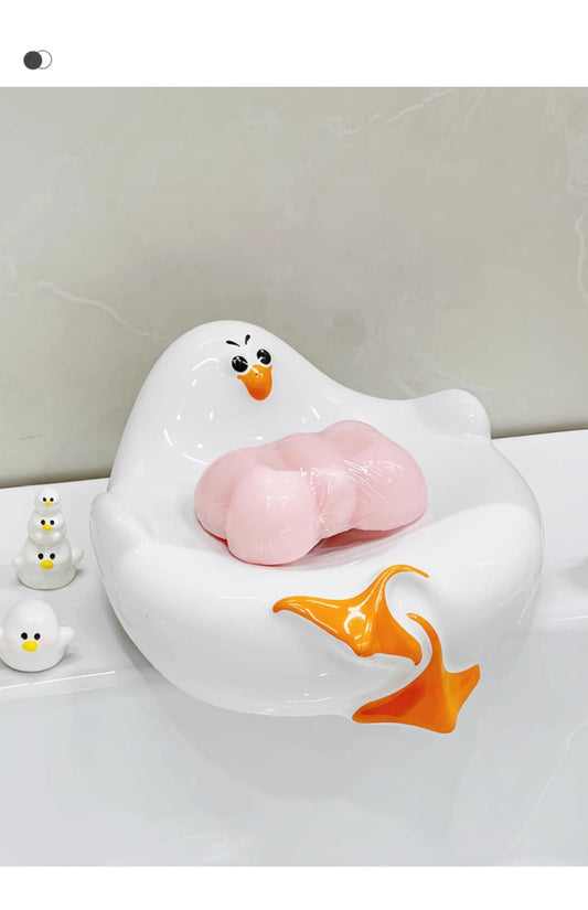 White ceramic seagull soap dish with drainage, holding a pink soap bar
