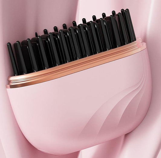 Pink cordless hair straightening brush with black heated bristles and gold trim