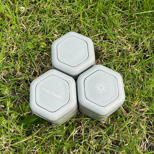 Three grey travel cosmetic containers with octagonal snap lids and icons