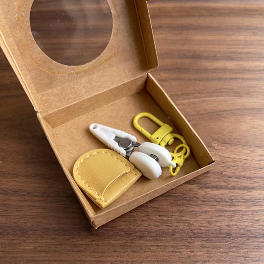 Yellow mini precision scissors with safety caps, leather sheath, and keychain hook