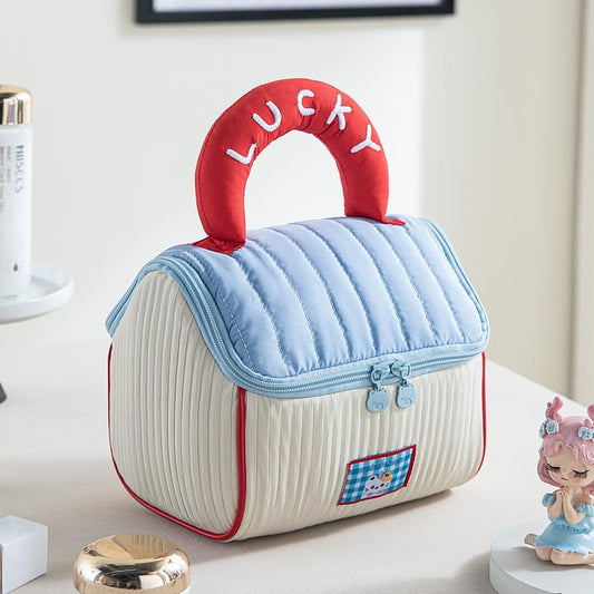 Quilted cosmetic bag with blue handle and red-trimmed dual zipper, white striped body