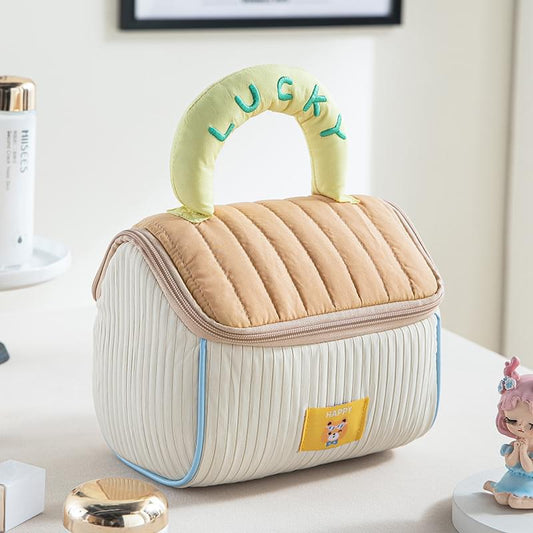 Quilted cosmetic bag in cream with vertical stripes, tan top panel, pale green handle