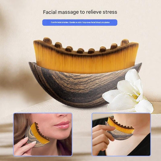 Curved facial massage brush with golden nylon bristles and dark gray textured backing
