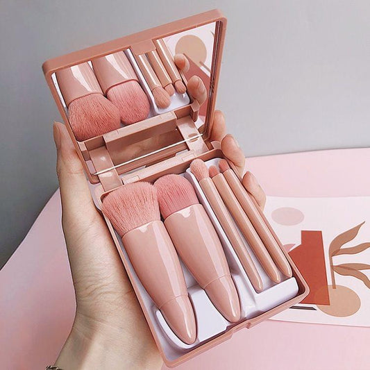 Compact makeup brush set with open mirror and five pink synthetic brushes in case