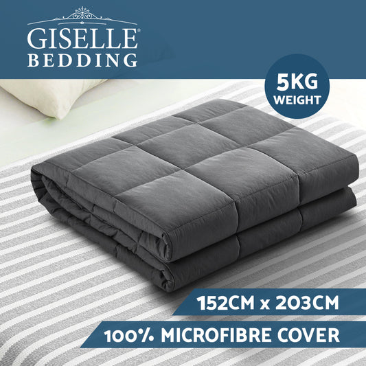 Dark grey quilted weighted blanket laid flat on striped bedding