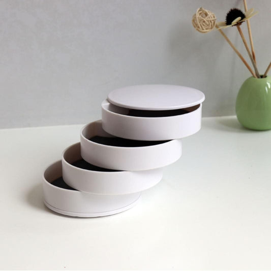 Rotating jewelry storage box with four white circular layers and dark velvet lining