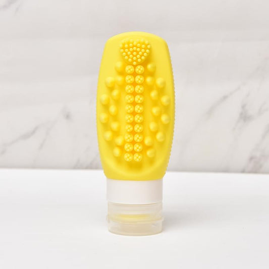 Yellow silicone refillable squeeze bottle with textured massage brush head and refill cap