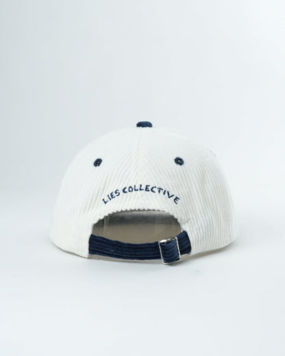 White knit cap with navy brim, LIES COLLECTIVE lettering, and adjustable strap back
