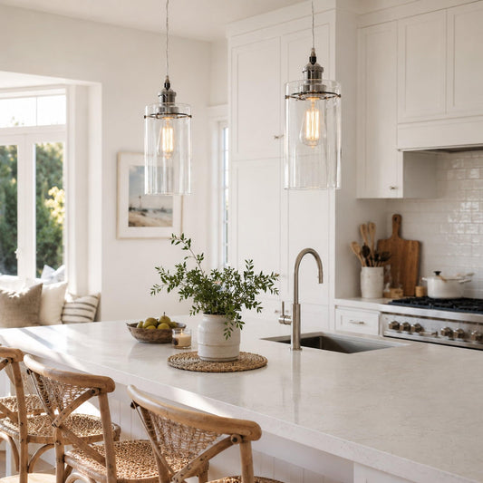 Set of two glass cylinder pendant lights with chrome caps and warm exposed bulbs.
