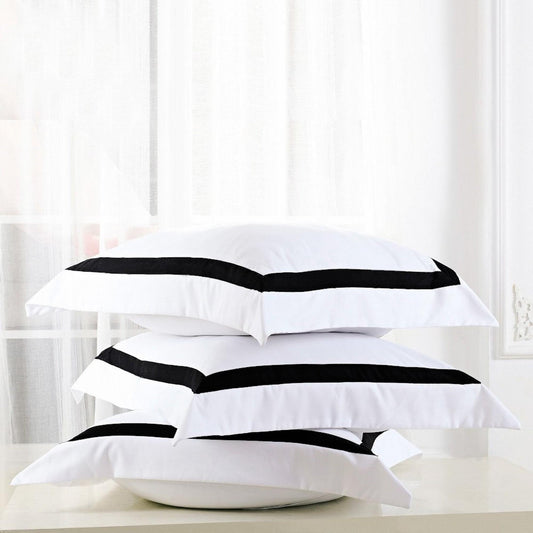 White European pillowcases with bold black piping, stacked on a pillow.