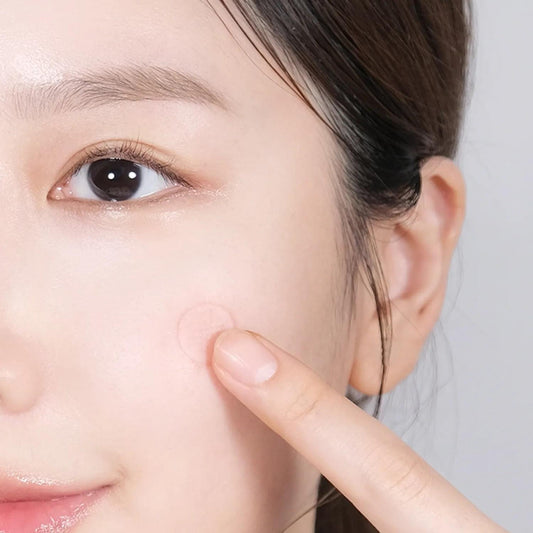 Cica micro spot patch on cheek, finger applying small adhesive patch