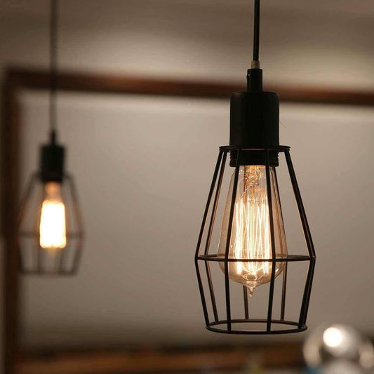 Black industrial cage pendant light with glowing clear bulb inside