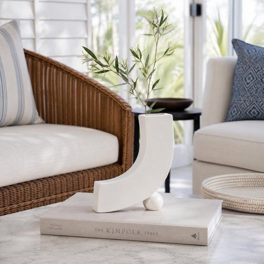 Ceramic blossom vase in white with curved cutout shape, styled with small greenery
