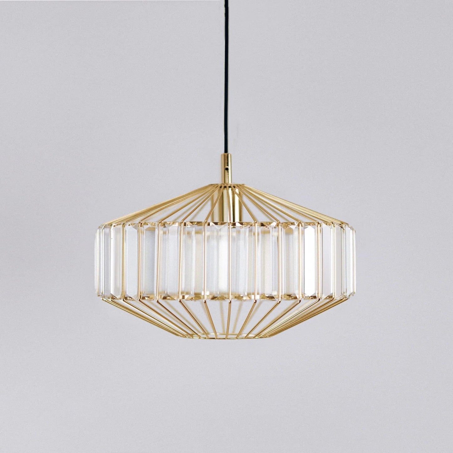 Gold prism glass pendant light with faceted clear panels and gold frame, hanging