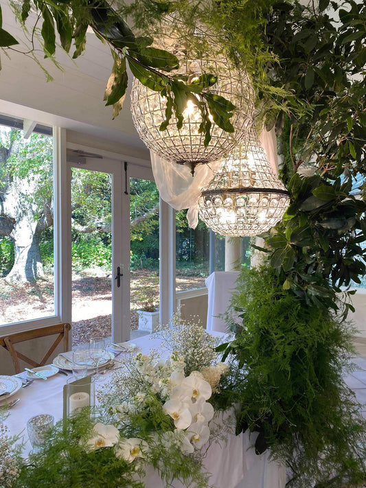 Brass crystal pendant globe chandelier hanging above an outdoor event table