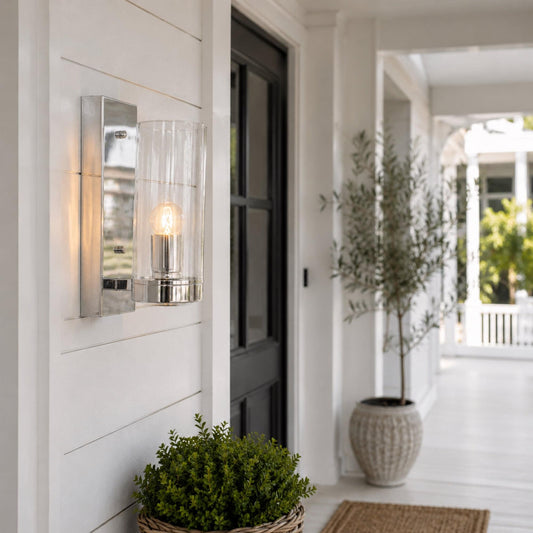 Chrome wall pendant light with clear glass shade on a modern exterior wall.