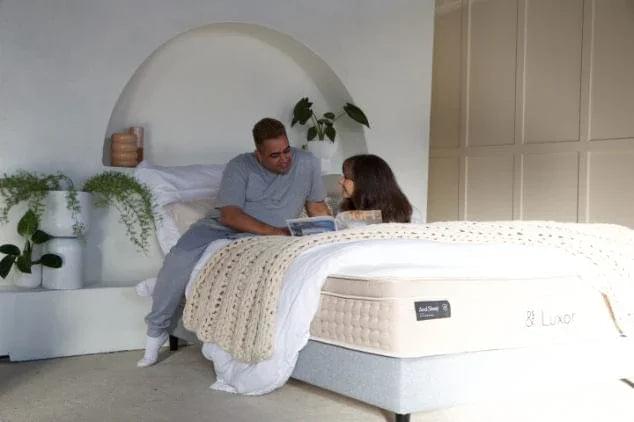 White mattress in bedroom setting, featuring & Luxor panel on the side