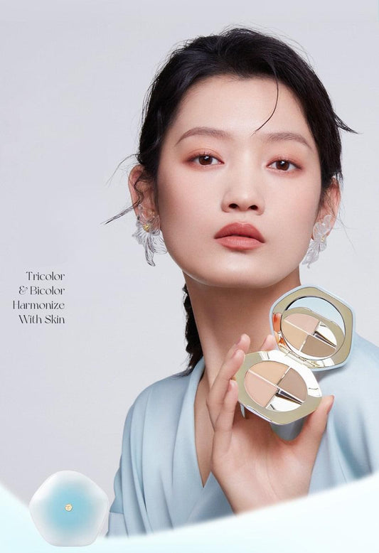 Concealer palette compact held by model, showing four beige shade pans