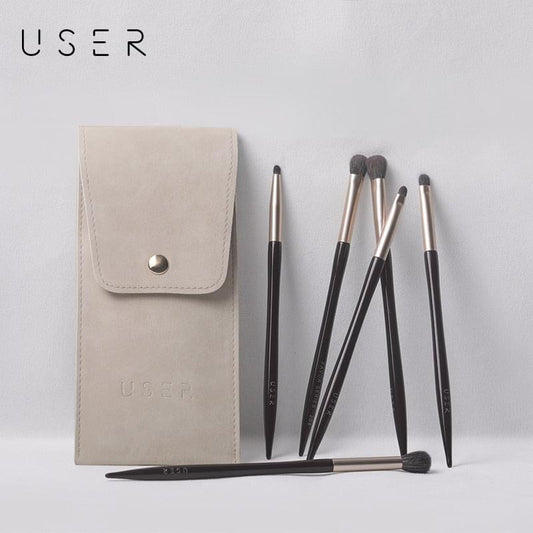 Seven eye makeup brushes with beige snap pouch; black handles and silver ferrules