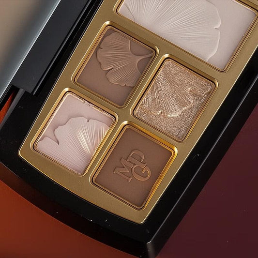 Close-up of pressed powder pans with contour and shimmer shades in gold tray