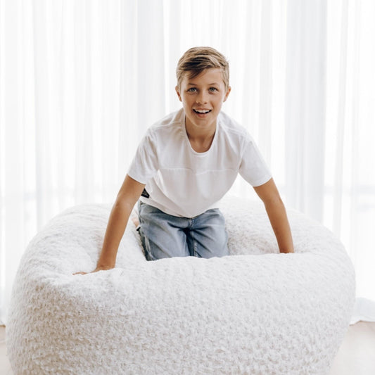 White plush bean bag chair with thick seat, child sitting and leaning forward