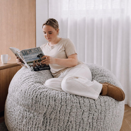 Light gray textured round pouf with stitched crepe-like surface