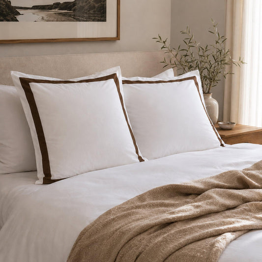 White European pillowcase set with brown trim, shown on bed