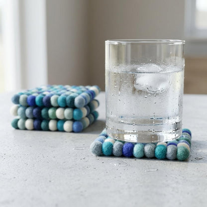 Round wool felt coaster with multicolor pom-pom edge in blue, green, and cream